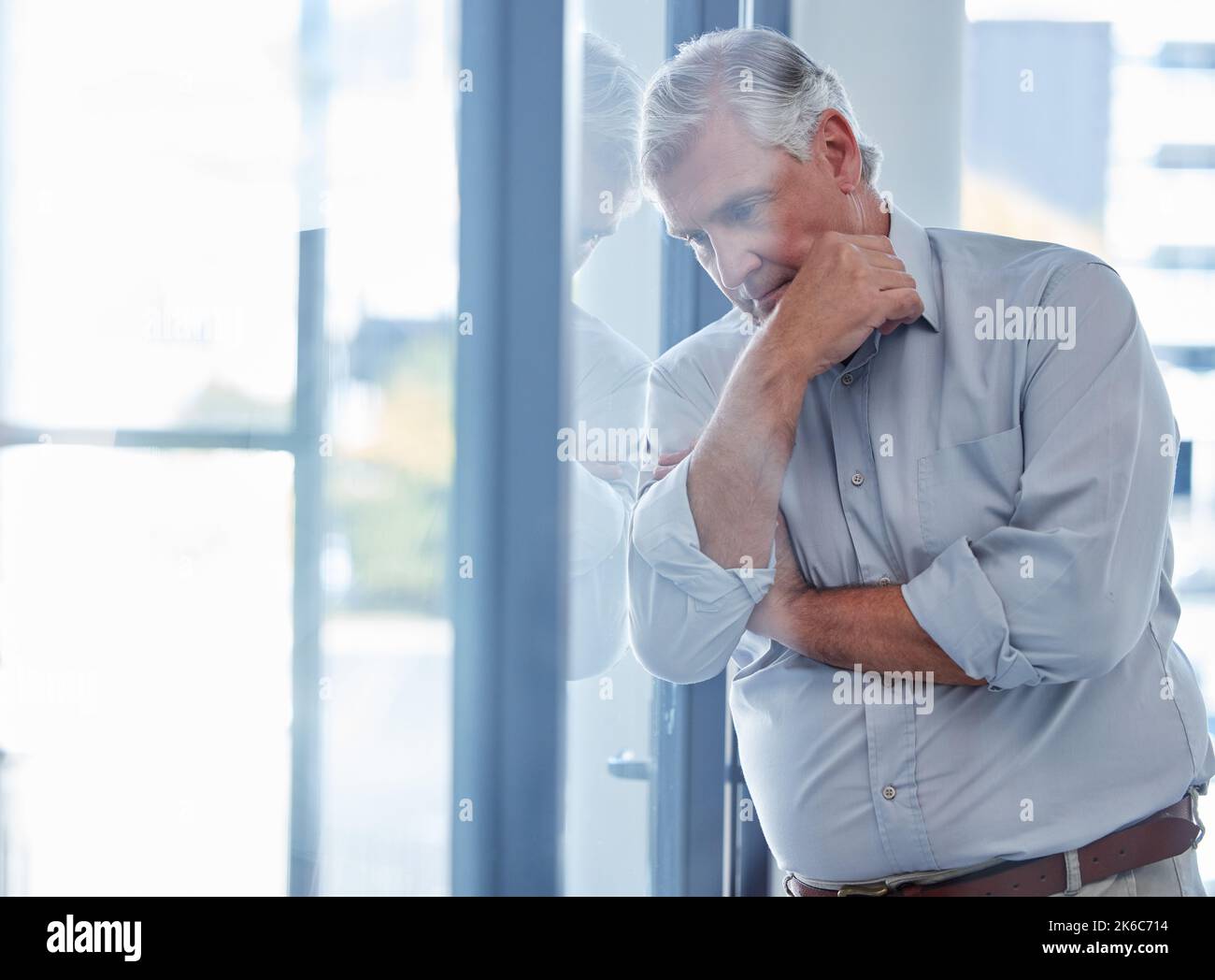 Ich fürchte immer um die Zukunft meines Unternehmens. Ein reifer Geschäftsmann, der gestresst vor einem Fenster in einem Büro steht. Stockfoto