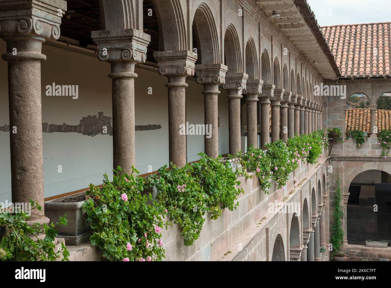 Offene Terrasse im zweiten Stock mit Steinsäulen und frischen Blumen des alten spanischen Gebäudes Stockfoto