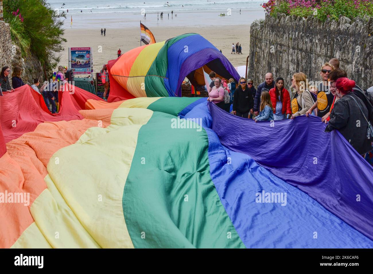 Das riesige bunte Cornwall ist stolz auf das Pride-Flaggenbanner, das von den Teilnehmern der Parade im Zentrum von Newquay in Großbritannien gehalten wird. Stockfoto