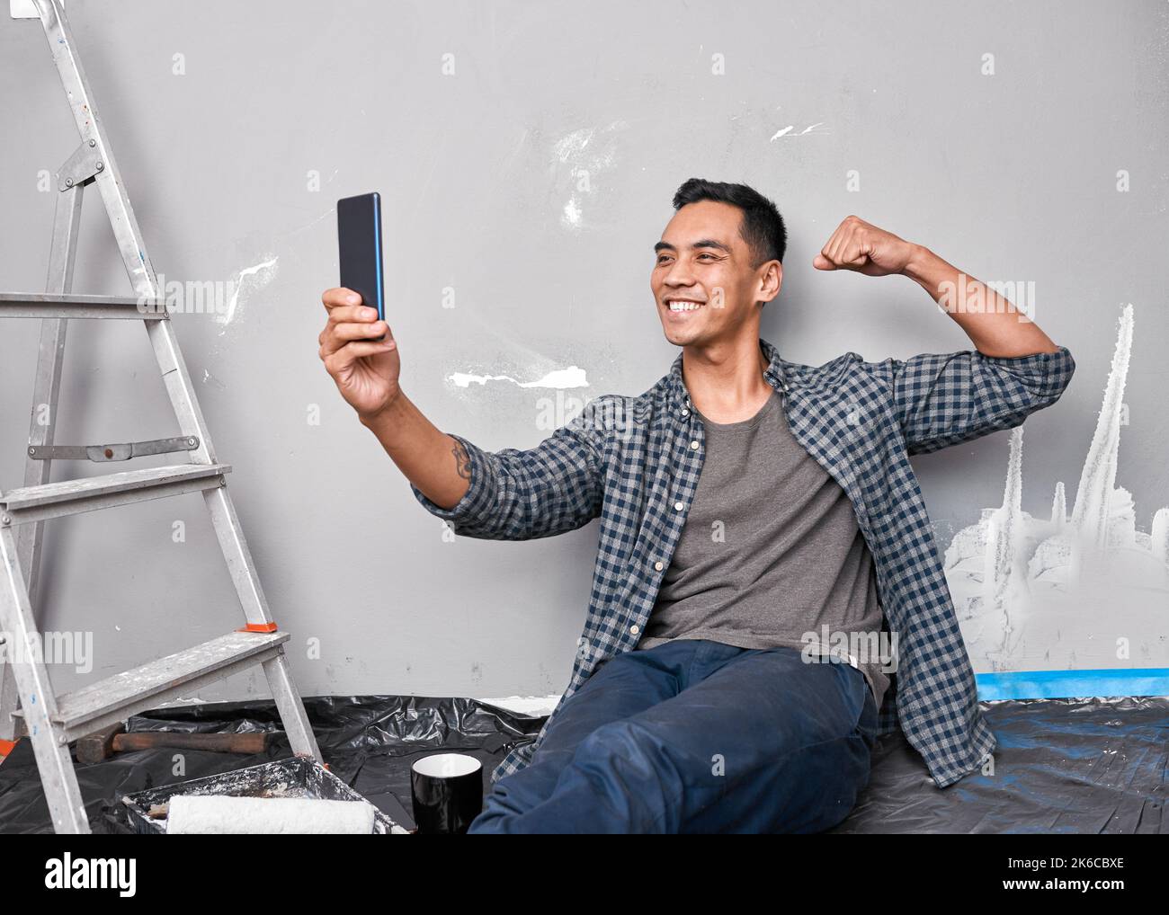 Ein junger asiatischer Mann nimmt ein Selfie, während er mit Heimwerkerprojekt beschäftigt ist Stockfoto