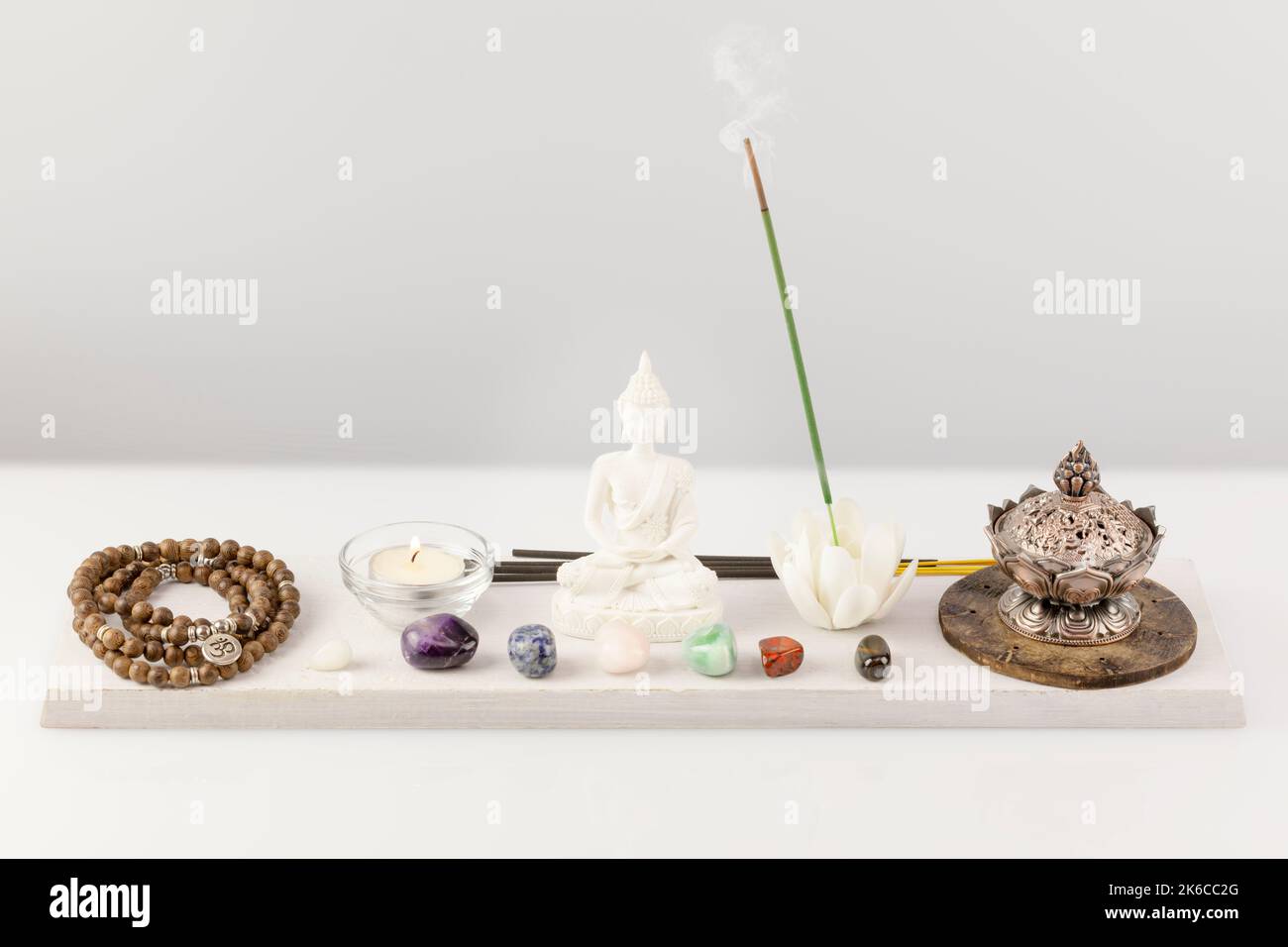 Rosenkranz-Perlen, Aromaschale, Duftstäbchen, buddha-Figur, Chakra-Steine und Kerze Stockfoto