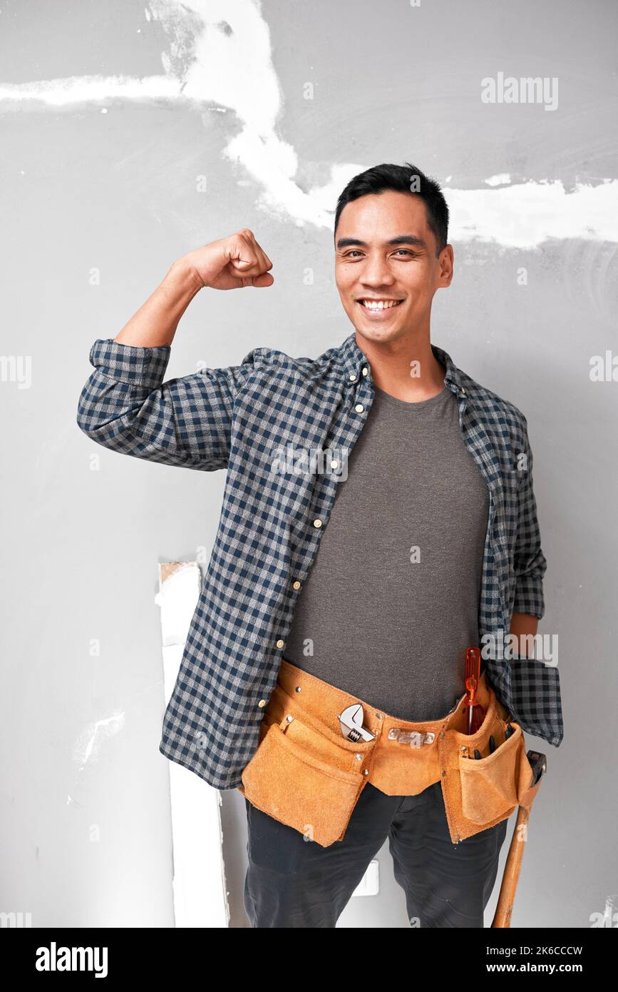 Ein attraktiver junger asiatischer Mann posiert mit starkem Arm, während er Heimarbeit leistet Stockfoto