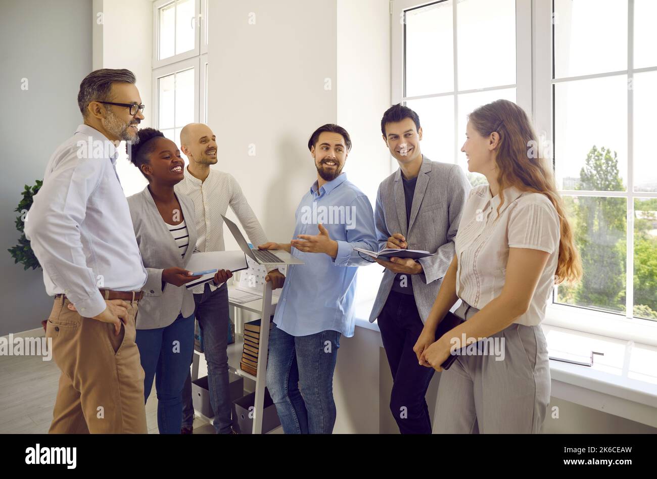 Lächelnde Gruppe von erwachsenen Studenten diskutieren etwas in der Pause im Büro, Universität. Stockfoto