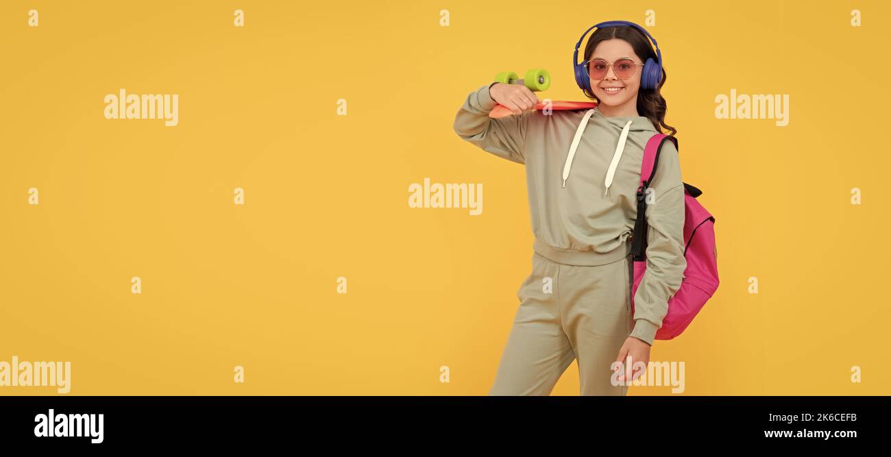 Fröhlicher Teenager in aktivem Ohr, der auf gelbem Hintergrund Pennyboard hält, Board Skating. Lässiges horizontales Poster für Teenager-Kinder. Banner-Kopfzeile, Kopierbereich. Stockfoto