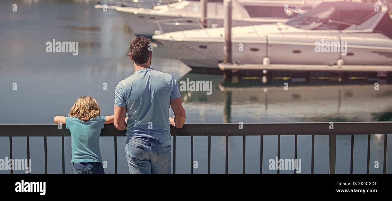 Sommerbanner, Elternschaft und Vaterschaft. Vatertag. Vater und Sohn blicken auf Yachten im Hafen. Stockfoto