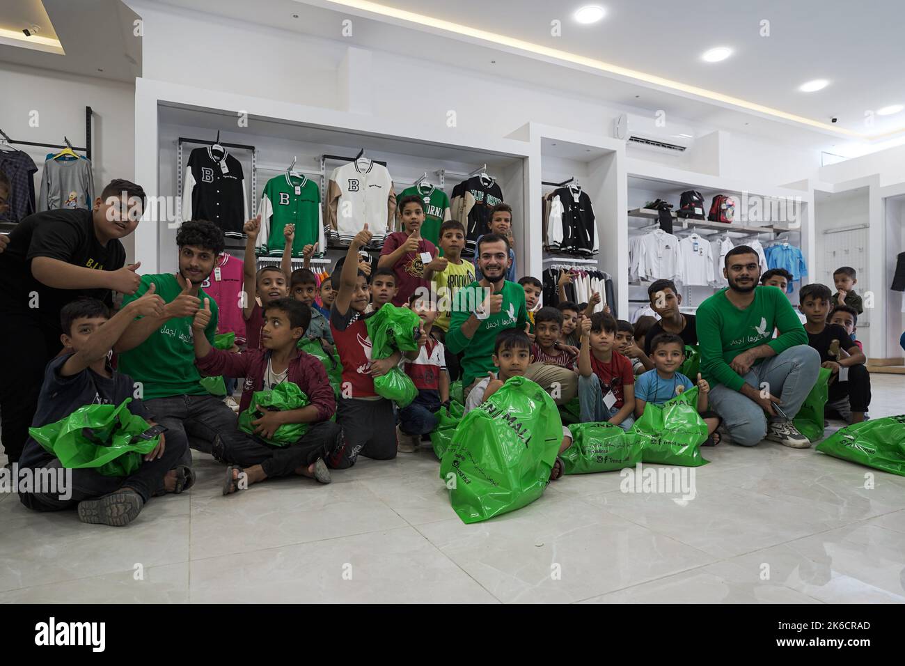 Mosul, Irak. 09. Oktober 2022. Mitglieder der Khaloohajmal Foundation posieren für ein Foto mit verwaisten Jungen im Einkaufszentrum. Die Khaloohaajmal Foundation bereitet 1000 Waisenkinder mit Schulbedarf wie Uniformen, Taschen und Schreibwaren vor, um sich auf das neue Schuljahr in der Stadt Mosul im Nordirak vorzubereiten. Kredit: SOPA Images Limited/Alamy Live Nachrichten Stockfoto