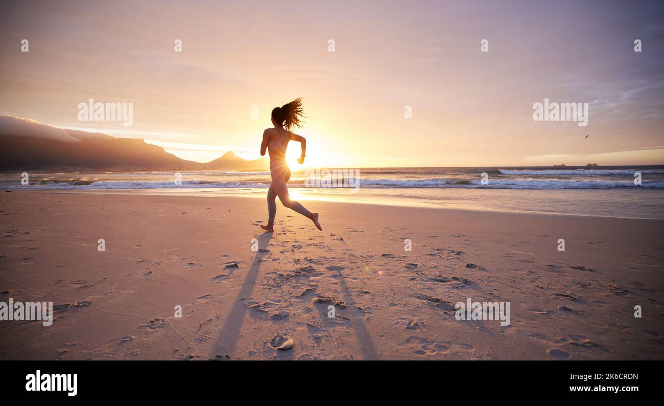 Eine junge Frau, die am Strand Yoga praktiziert, macht alles möglich, um gesund zu leben. Stockfoto