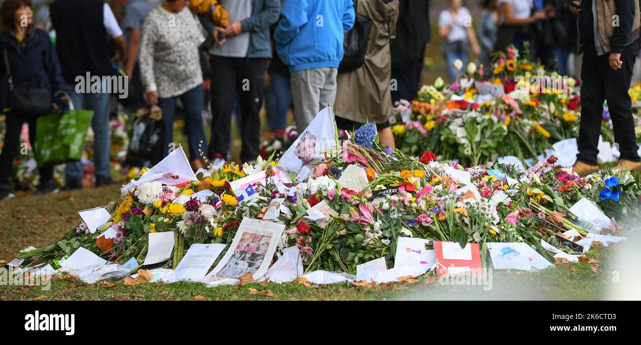 Blumen und Ehrungen, darunter eine Flagge mit dem Queens-Portrait, das im Green Park London UK angebracht ist. Stockfoto