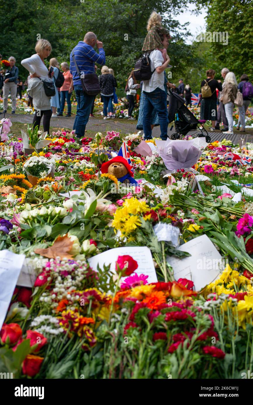 Ein Paddington-Bär sitzt unter den Blumengedenken an die Queen, die im Green Park London in Großbritannien platziert wurden. Die Menschen zeigen der verstorbenen Königin ihren Respekt. Stockfoto