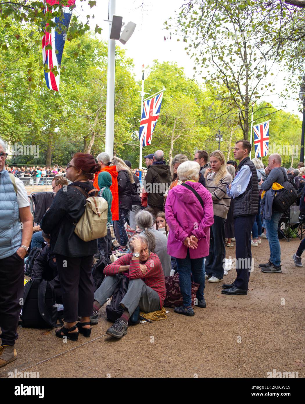 Mitglieder der Öffentlichkeit sitzen und warten auf der Mall, nachdem sie sich ihre Plätze gesichert haben, um den Queens Coffin und die königliche Familie in Richtung Windsor Hall zu sehen. Stockfoto