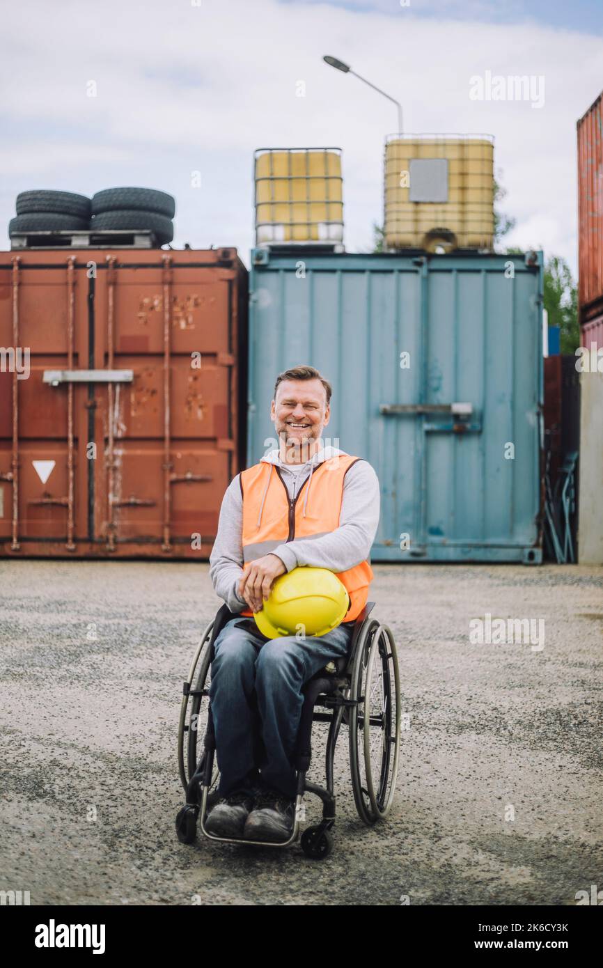 Porträt eines lächelnden Bauarbeiters, der auf der Baustelle im Rollstuhl sitzt Stockfoto