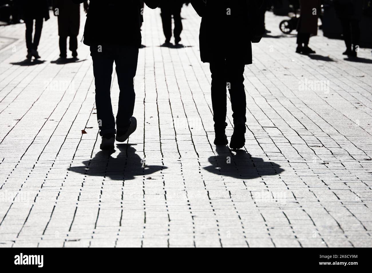 Silhouetten und Schatten von Menschen auf der Straße. Menschenmenge, die auf dem Bürgersteig, dem Konzept von Gesellschaft und Bevölkerung herunterkommt Stockfoto
