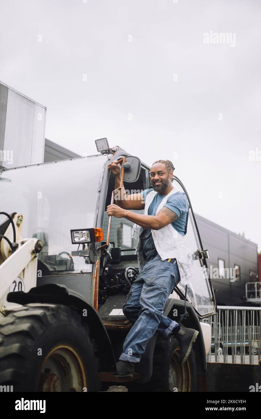 Die ganze Länge des Bauarbeiters, der am Eingang des Fahrzeugs steht Stockfoto