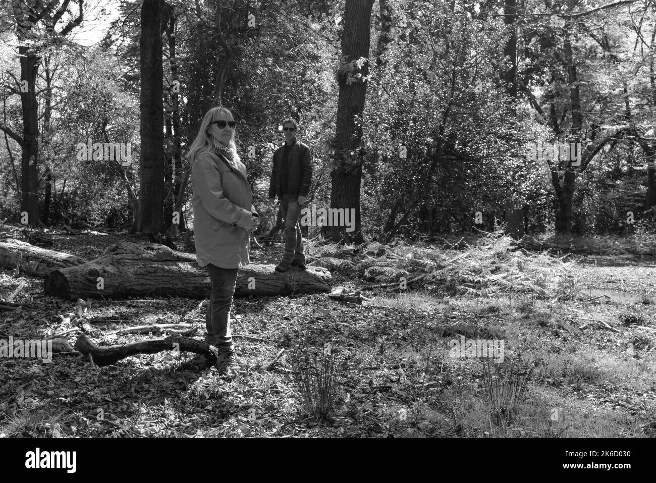 Paar, Frau und Mann, stehen in Wald oder Wald in gestaffelten Positionen und blicken mit Haltung auf die Kamera. Schwarz und Weiß. Stockfoto