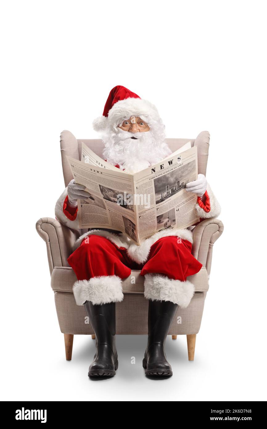 Der weihnachtsmann sitzt im Sessel und liest Zeitung isoliert auf weißem Hintergrund Stockfoto