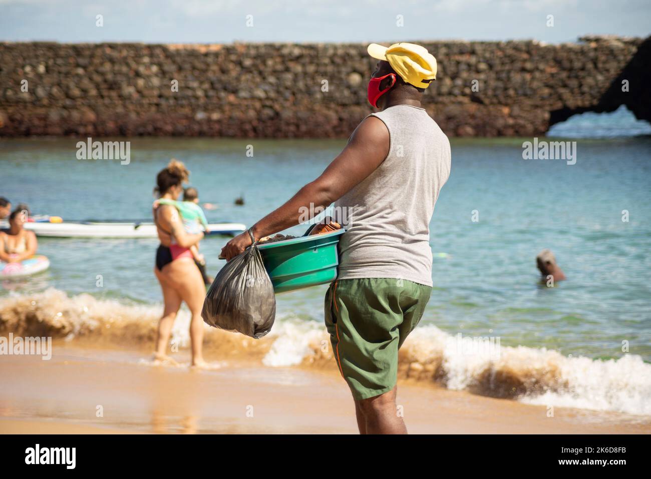 Salvador, Bahia, Brasilien - 04. Juni 2022: Straßenverkäufer laufen auf dem Sand des Strandes von Porto da Barra in Salvador, Bahia. Stockfoto