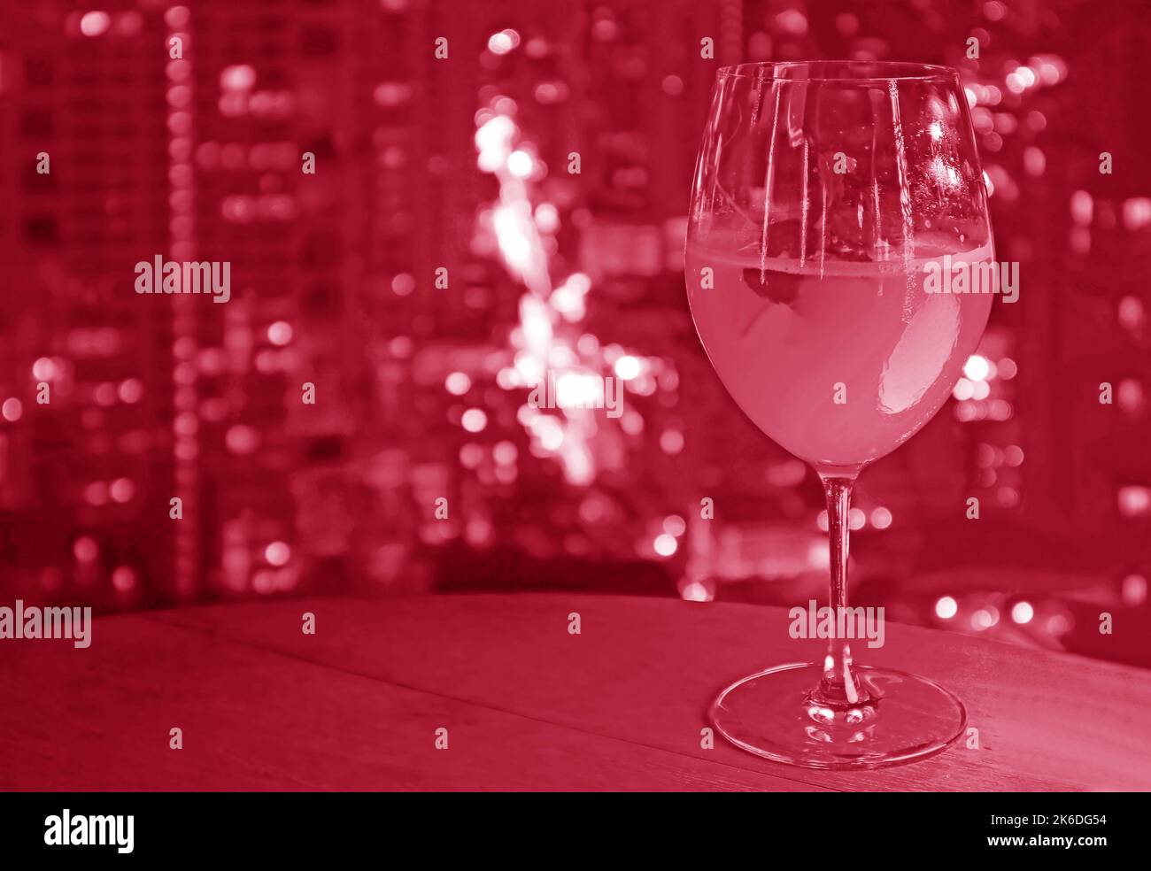Hibiskusfarbenes Glas Cocktail im Pop-Art-Stil mit verschwommener Luftaufnahme in der Stadt im Hintergrund Stockfoto