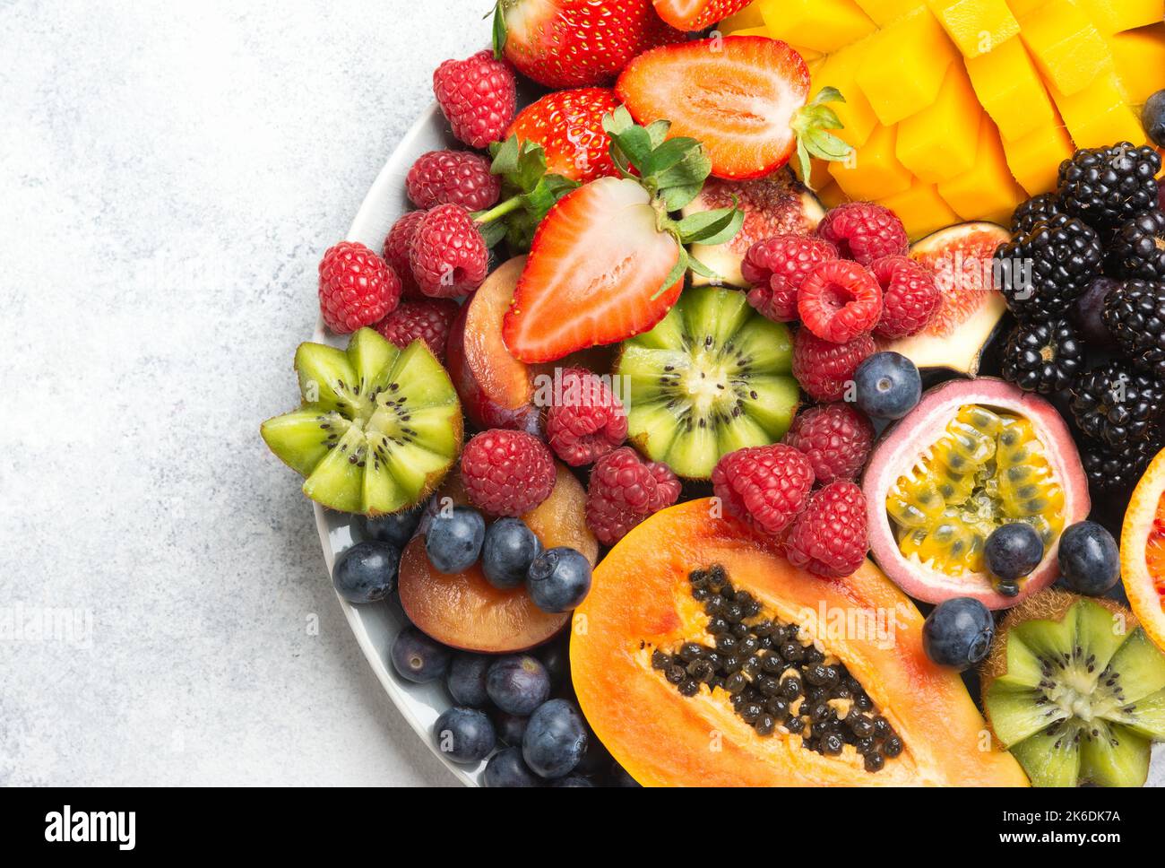 Köstliche Früchte auf weißem Hintergrund, Mangopatapfel Himbeeren Papaya Orangen Passionsfrüchte Beeren, selektiver Fokus, Draufsicht Stockfoto