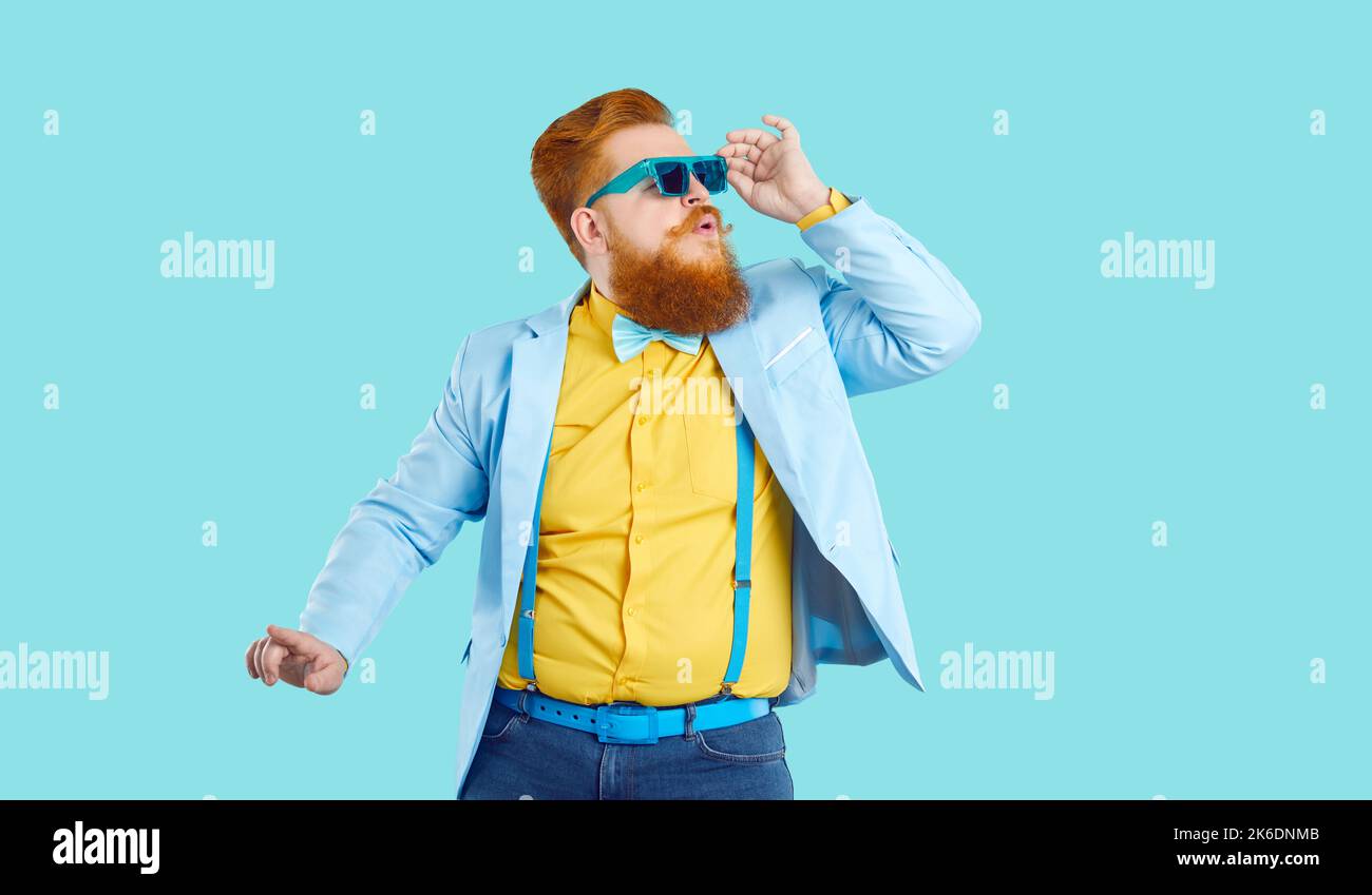 Lustige mollige junge bärtige Mode Kerl in funky Outfit tanzen auf blauem Hintergrund Stockfoto