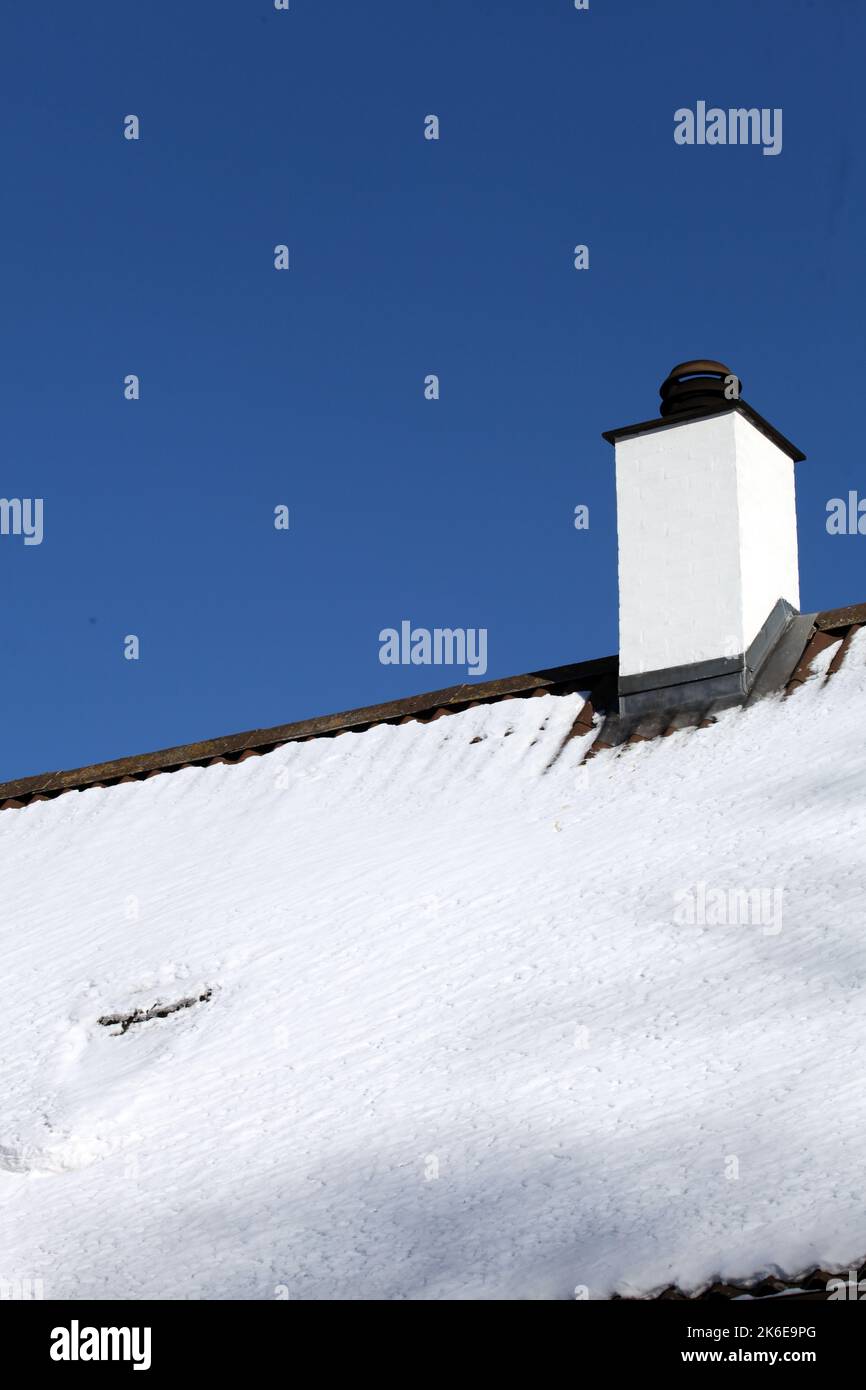 Weißer Kamin und Dach mit Schnee. Ein kalter Winter und möglicherweise Mangel an Brennstoff und Brennholz Stockfoto