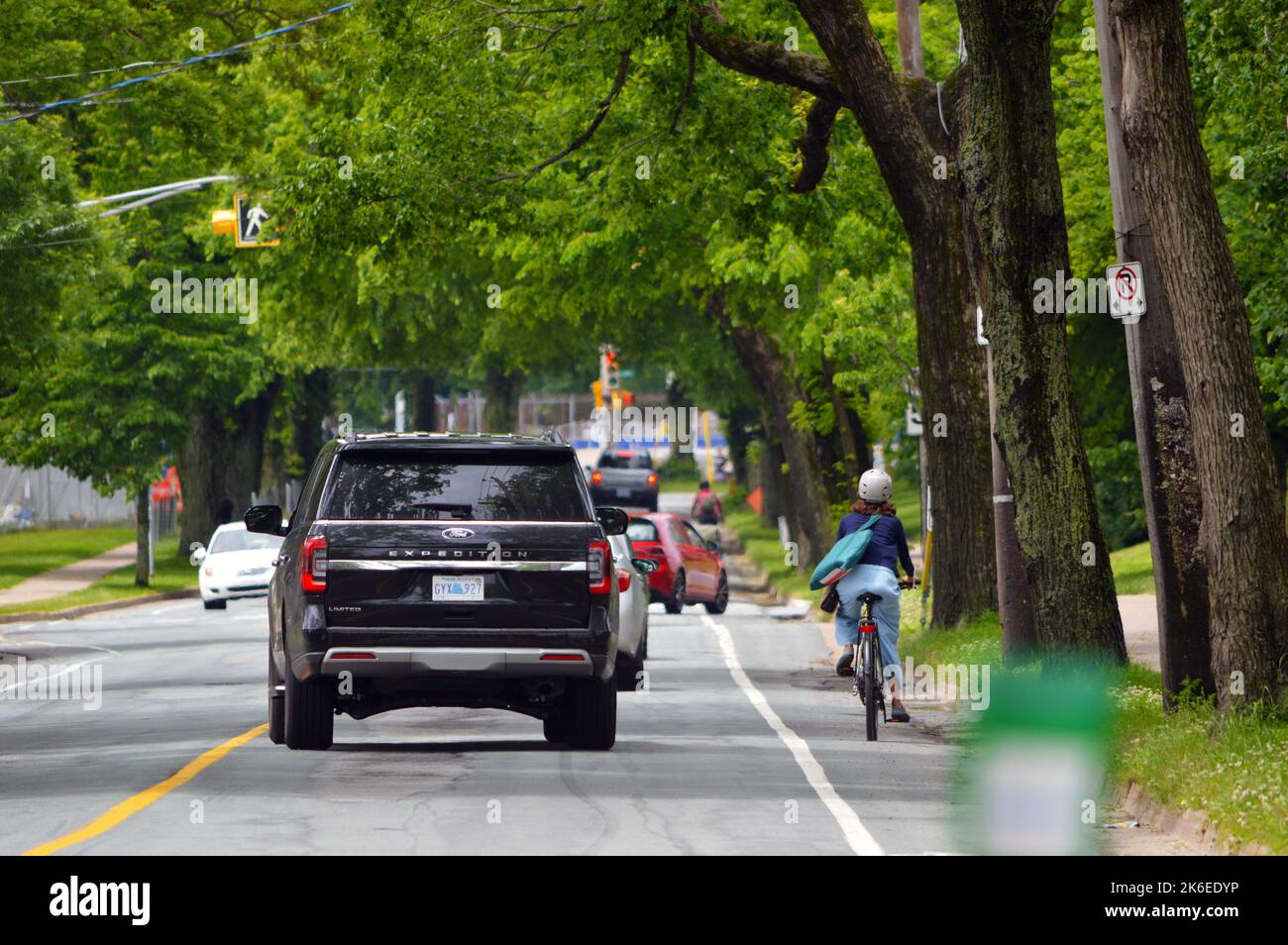 Radfahrer, die neben dem Autoverkehr in Halifax, Kanada, die Fahrradspur der Bell Road benutzen (2022) Stockfoto