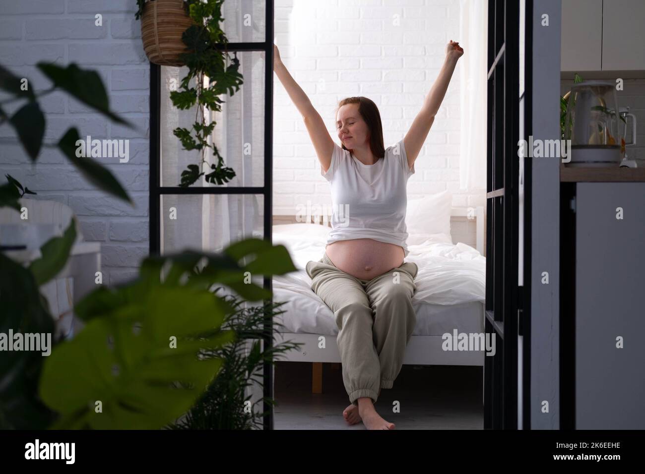 Schwanger glücklich Morgen werdende Mutter aufwachen streicheln ihren Bauch. Frau Hände berühren ihren Bauch, warten Kind, sitzen auf dem Bett Vorbereitung für Stockfoto