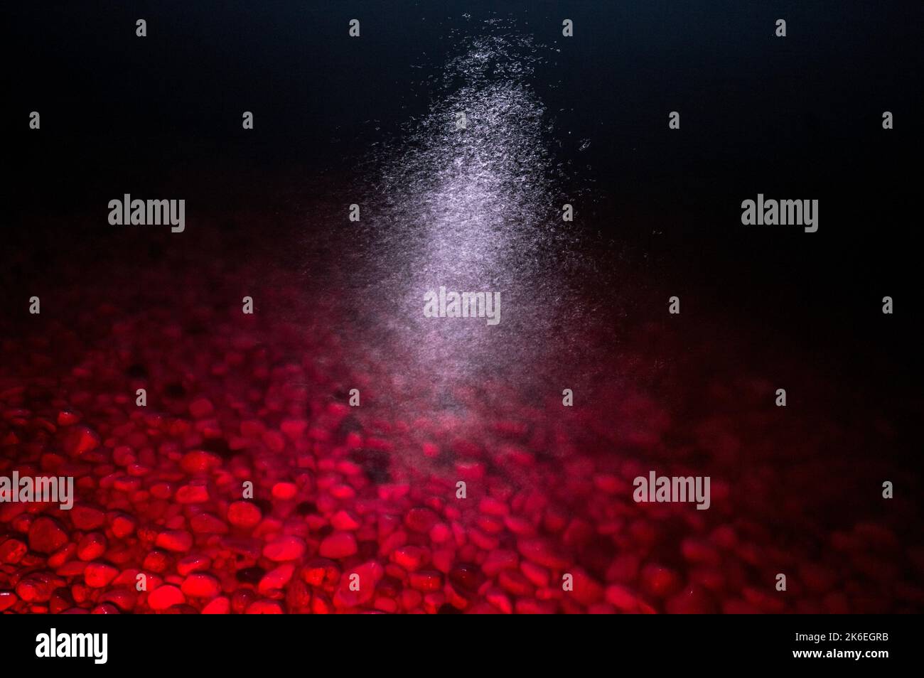 Rotes Licht leuchtete auf Unterwasserfelsen, Seeufer in der Nacht, Mondlicht an der Oberfläche Stockfoto