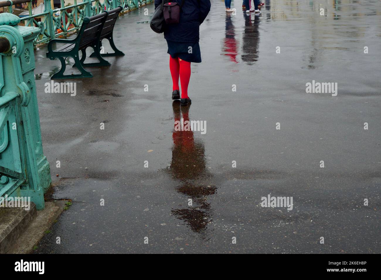 Frau in roten Strümpfen, die im Regen läuft, Brighton, England, Großbritannien Stockfoto