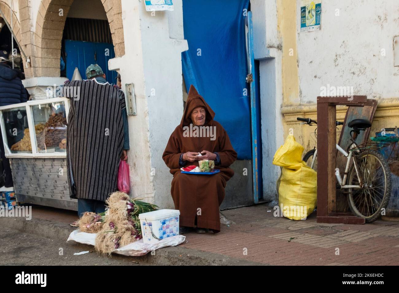 Zwei marokkanische Männer in traditioneller Kleidung, die Lebensmittel in der historischen Altstadt von Medina, Essaouira, Nordafrika, verkaufen und kaufen Stockfoto