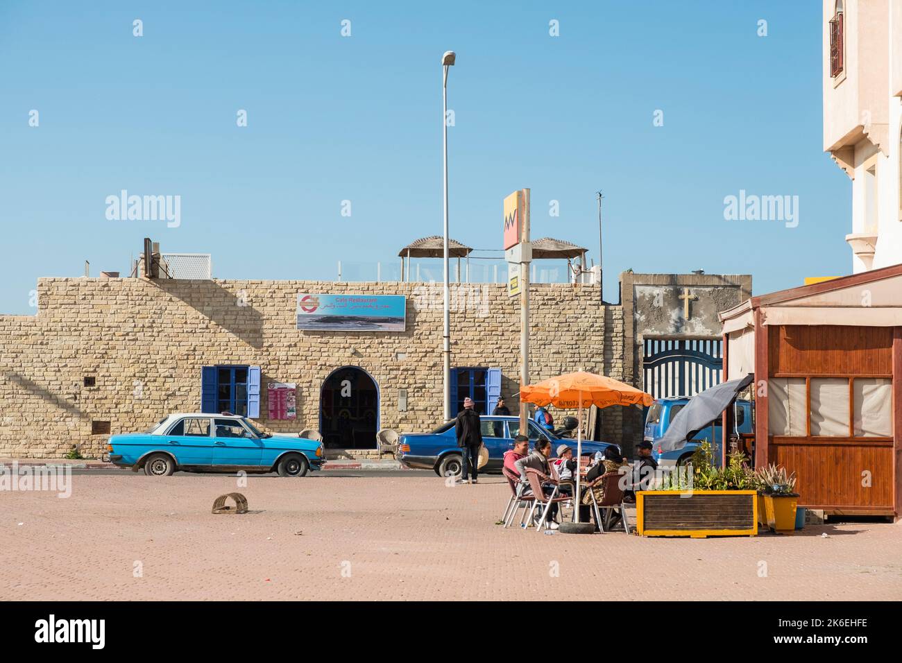 Eine Familie isst im Freien unter einem Sonnenschirm in einem Restaurant in der historischen Altstadt von Essaouira, Marokko, Nordafrika Stockfoto