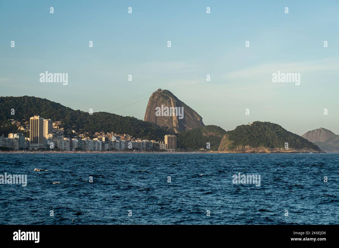 Weiter Blick auf die Copacabana und Leme Strände Küste mit dem hohen Zuckerhut auf der Rückseite, wie vom Fort Copacabana am späten Nachmittag am blauen Himmel zu sehen. Stockfoto