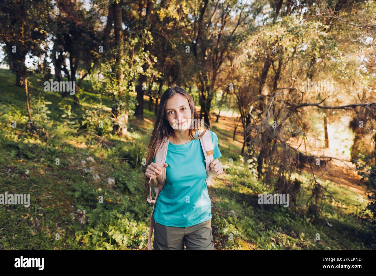 Selbstvertrauen. Teenager-Mädchen, die Kamera mit Rucksack mit heiterem Lächeln im Wald zu suchen. Stockfoto