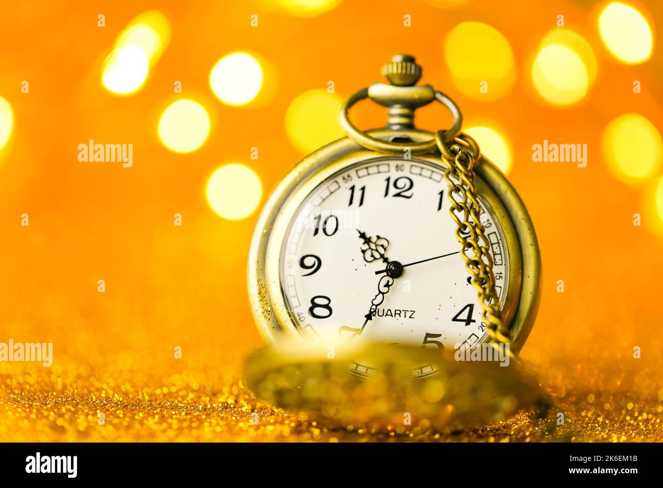 Weihnachtszeit.Goldene Uhr in Gold Glitter mit glänzenden Bokeh.Weihnachtszeit.Weihnachtstapete.Feiertagslichter.schöner Hintergrund in warmen goldenen Stockfoto