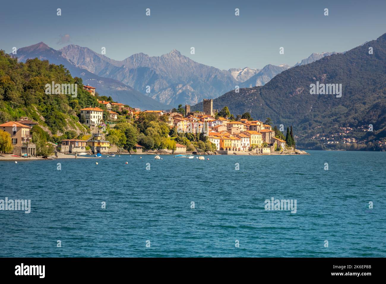 Idyllische Küste am Comer See mit Dorf und Schnellboot an sonnigen Tagen, Italien Stockfoto