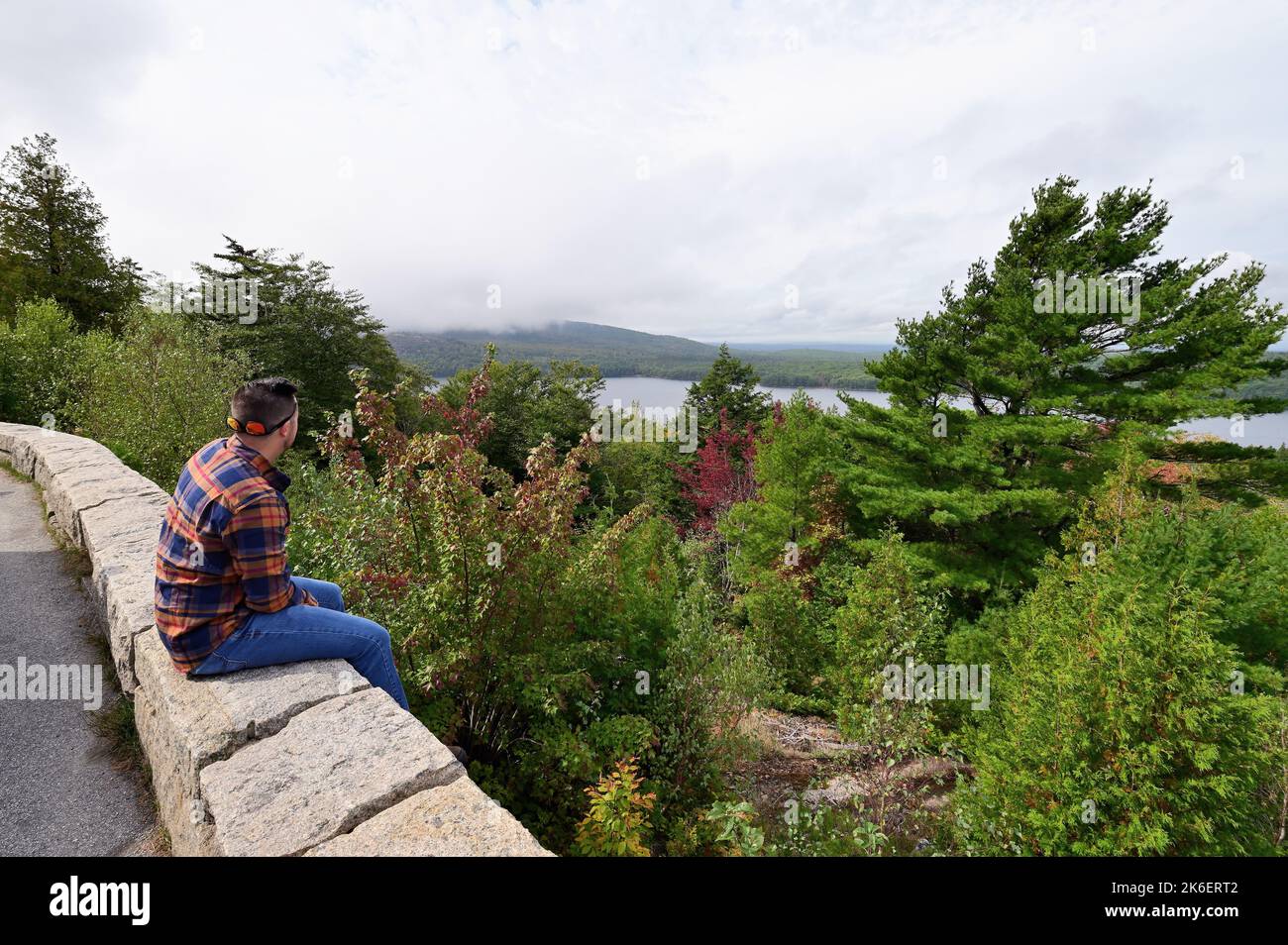 Acadia National Park, Maine, USA. Der Mensch, der die Aussicht auf den frühen Herbst in den Bäumen über dem Eagle Lake zu zeigen beginnt. Stockfoto