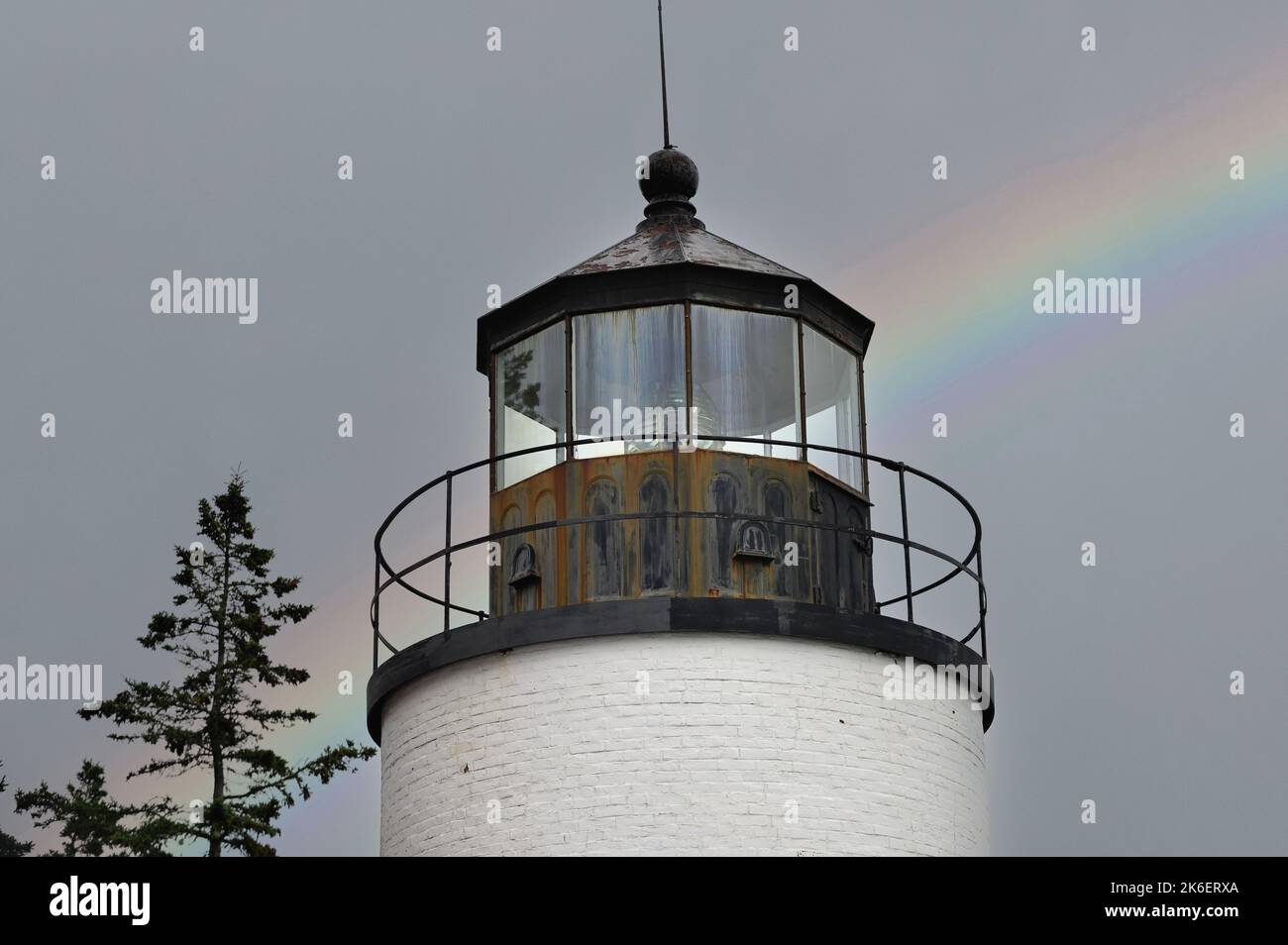 Acadia National Park, Maine, USA. Ein Regenbogen, der aus Nebel und Nebel hinter der Bass Harbor Head Light Station auftaucht, wurde 1858 errichtet. Stockfoto