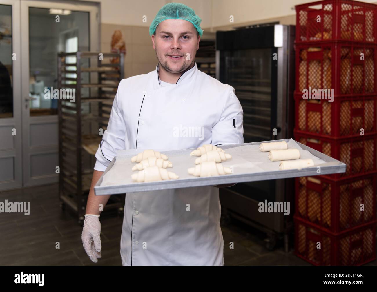 Junger Konditormeister bereitet im Backwarenkochverfahren Croissants zu, bevor er zum Ofen geht Stockfoto