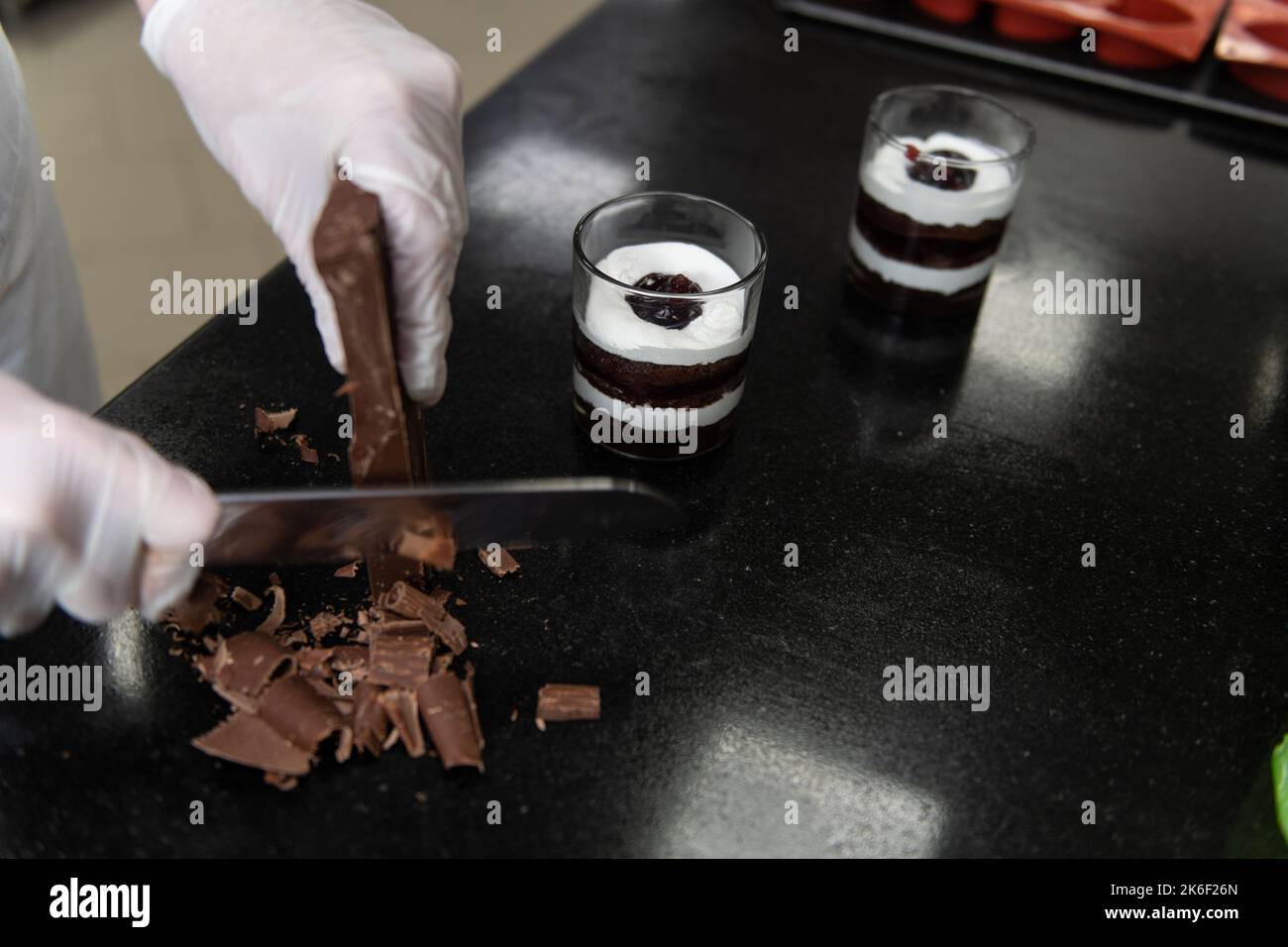 Chocolate Chef verwendet Knife Chop Dark Chocolate Bars zu klein für die Vorbereitung auf Schokolade Getränk zu machen Stockfoto