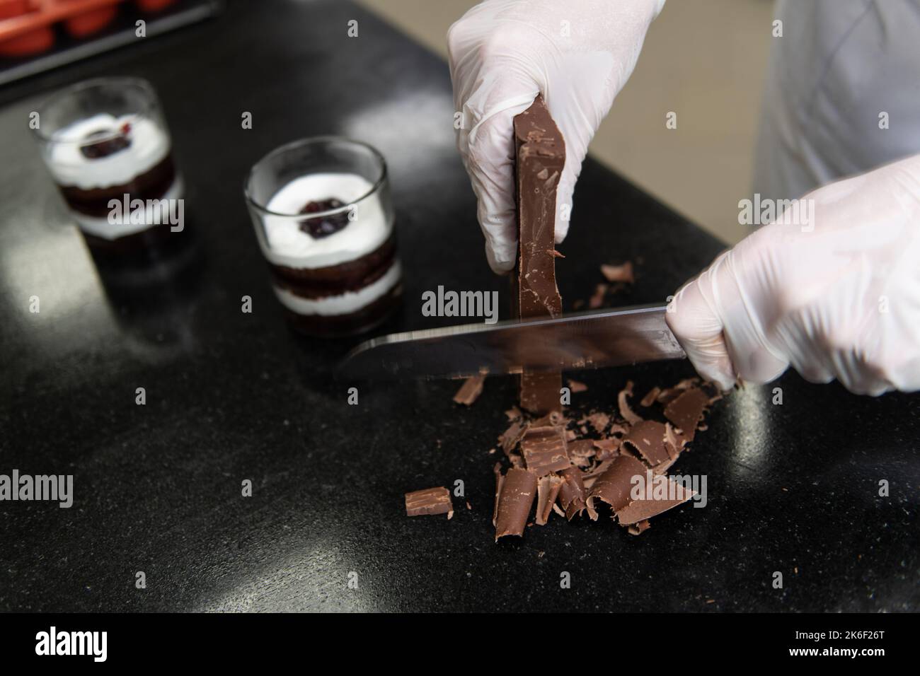 Chocolate Chef verwendet Knife Chop Dark Chocolate Bars zu klein für die Vorbereitung auf Schokolade Getränk zu machen Stockfoto