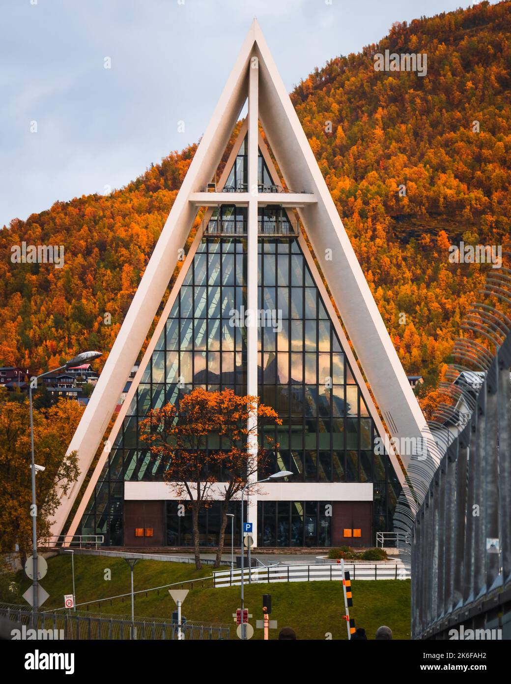 Eine vertikale Aufnahme der arktischen Kathedrale in Tromso, Norwegen, mit Herbstbäumen im Hintergrund Stockfoto
