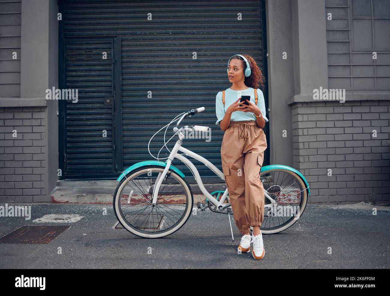 Telefon, Fahrrad und Stadtreisen für Frauen mit Musik-Kopfhörern, Podcast oder Radio in London City. Denkende Mode Student, mobile oder coole Modell mit eco Stockfoto