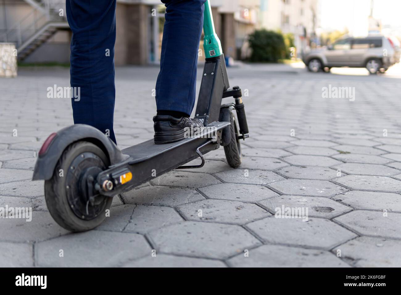Junger Geschäftsmann in einem Anzug auf einem Elektroroller auf einem Geschäftstreffen. Ökologisches Transportkonzept. Alternative Transportart altern Stockfoto