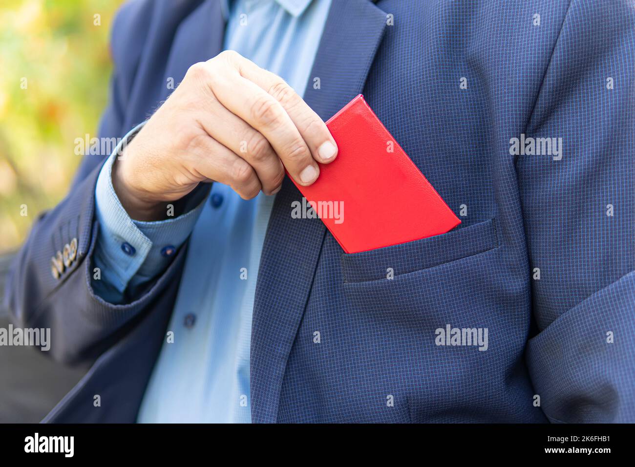 Ein Geschäftsmann in einem schwarzen Anzug zeigt seinen Personalausweis. Ein Beamter mit hohem Status zeigt sein rotes Dokument. Parlamentarische Immunität, leerer Personalausweis für tes Stockfoto