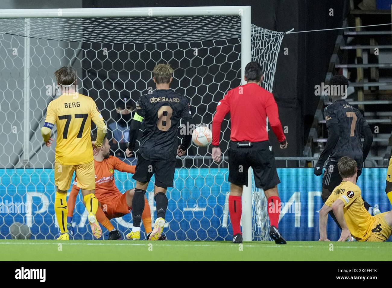 Bodø 20221013.Arsenals Bukayo Saka erzielt beim Fußballspiel in der Europa League zwischen Bodoe/Glimt und Arsenal im Aspmyra-Stadion das Tor von 1-0 hinter Bodoe/Glimts Torhüter Nikita Haikin. Bodoe/Glimts Patrick Berg und Arsenals Martin Oedegaard Foto: Fredrik Varfjell / NTB Stockfoto