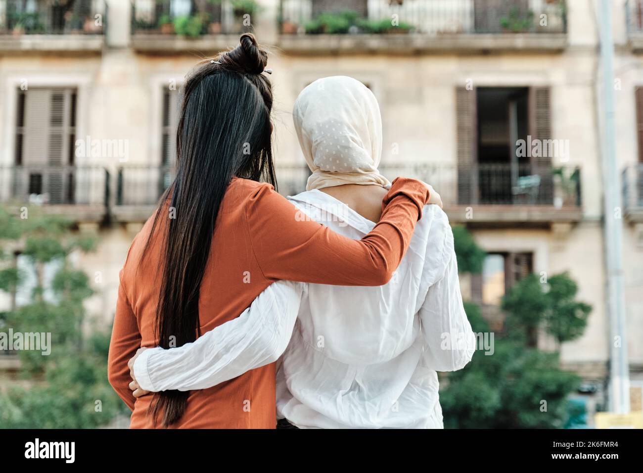 Multiethnische Freundinnen umarmen sich gegenseitig, während sie draußen auf der Straße stehen. Stockfoto