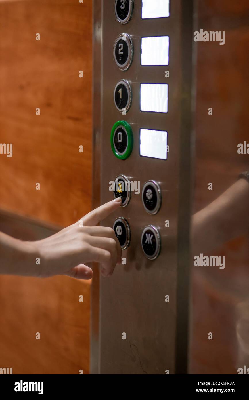 Die Hand einer Frau drückt einen Knopf im Aufzug, um Hilfe zu rufen. Moderner Aufzug. Stockfoto