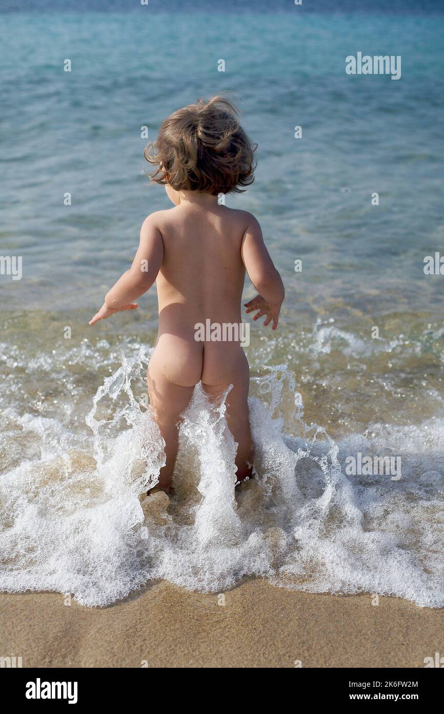 Kleines Baby, das am Strand steht und schwimmen geht. Baby Mädchen zu Fuß in das Meer Stockfoto