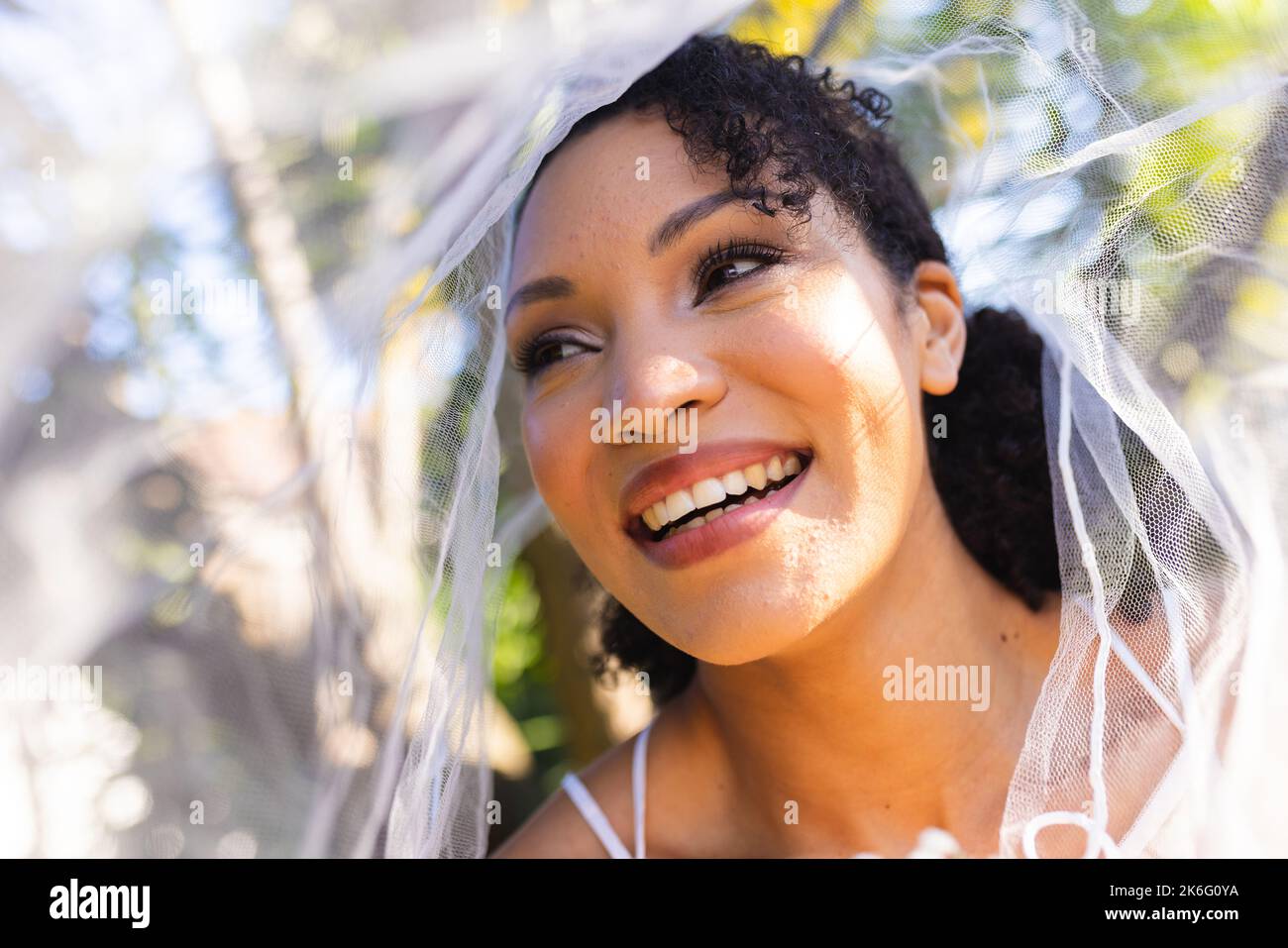 Eine glückliche afroamerikanische Frau, die am Hochzeitstag Hochzeitskleid und Schleier trägt Stockfoto