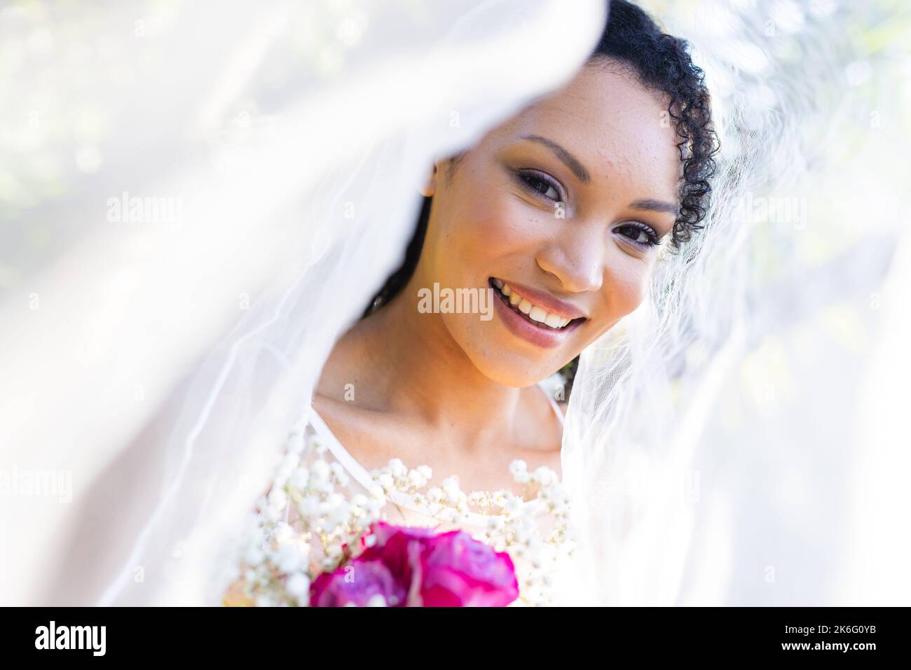 Porträt einer glücklichen afroamerikanischen Frau, die am Hochzeitstag Hochzeitskleid und Schleier trägt Stockfoto