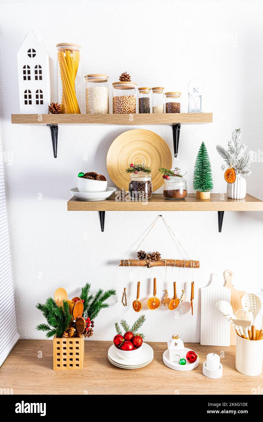 Vorderansicht von offenen Regalen und Arbeitsplatten mit verschiedenen Artikeln und hausgemachten Dekorationen für das neue Jahr und Weihnachten. Ökologisch saubere Küche Stockfoto